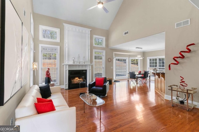 living room featuring ceiling fan, high vaulted ceiling, and light hardwood / wood-style flooring