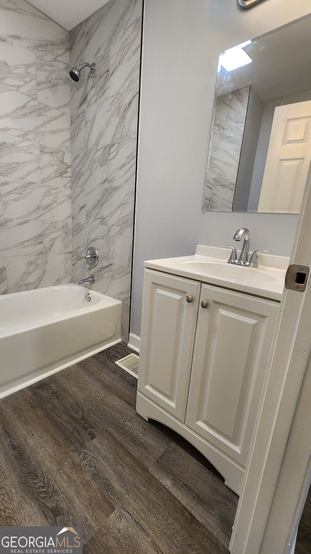 bathroom featuring hardwood / wood-style flooring, tiled shower / bath, and vanity