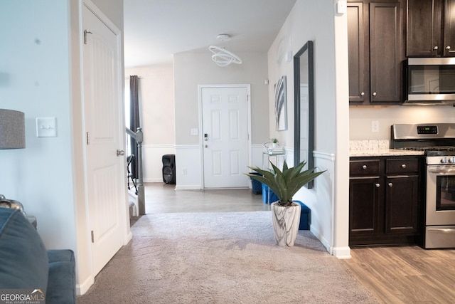 kitchen with light wood-type flooring, dark brown cabinets, and appliances with stainless steel finishes