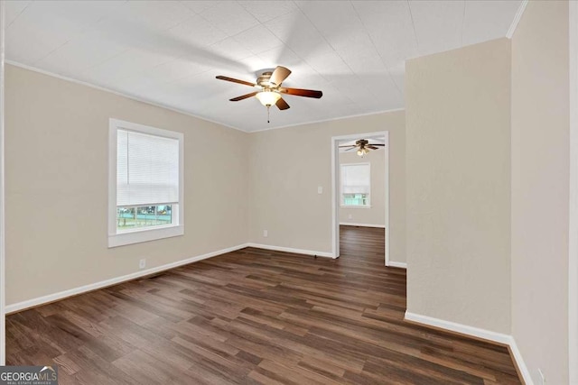 spare room featuring ceiling fan, a healthy amount of sunlight, crown molding, and dark wood-type flooring
