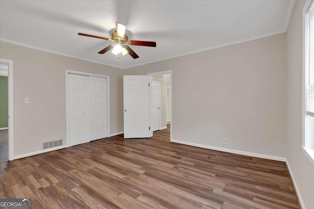 unfurnished bedroom with ornamental molding, baseboards, visible vents, and wood finished floors