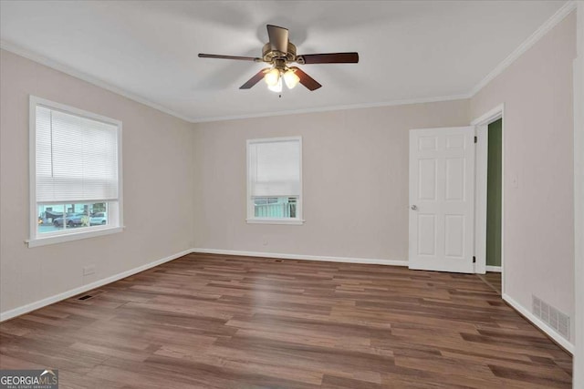 unfurnished room with crown molding, visible vents, wood finished floors, and a healthy amount of sunlight