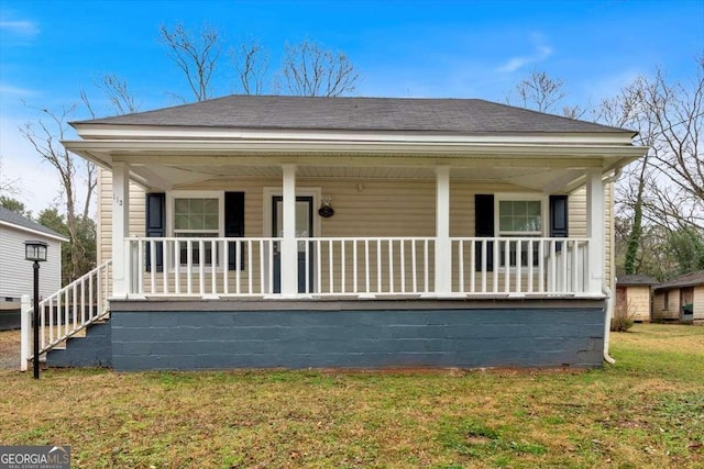 view of front of home with a porch, roof with shingles, and a front yard
