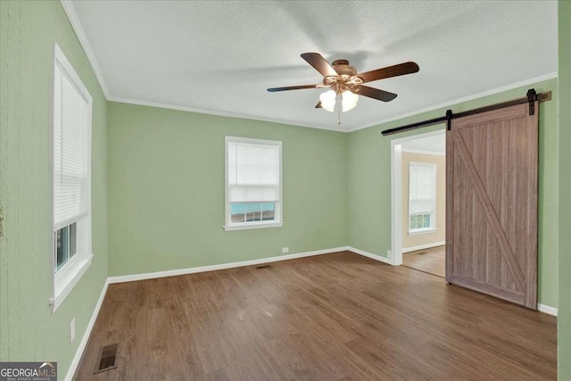 spare room featuring a ceiling fan, baseboards, visible vents, crown molding, and wood finished floors