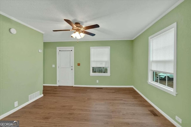 empty room featuring crown molding, ceiling fan, and visible vents
