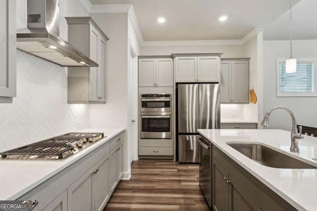 kitchen featuring wall chimney range hood, sink, gray cabinets, appliances with stainless steel finishes, and hanging light fixtures