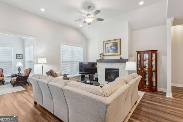 living room featuring a fireplace, dark wood-type flooring, ceiling fan, and vaulted ceiling