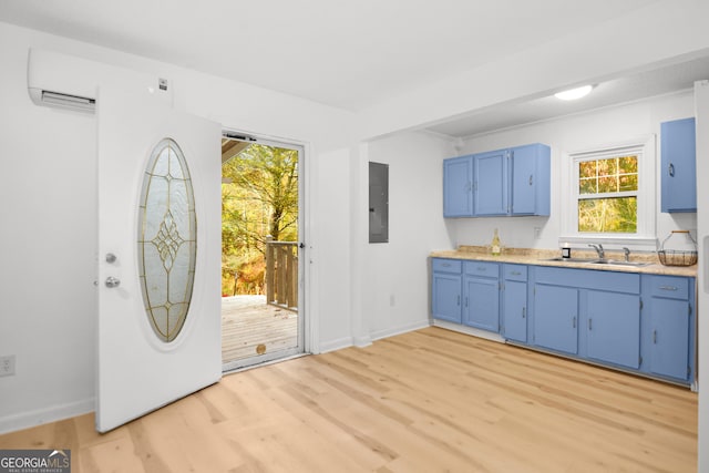 kitchen featuring sink, a wall mounted AC, electric panel, blue cabinetry, and light hardwood / wood-style flooring