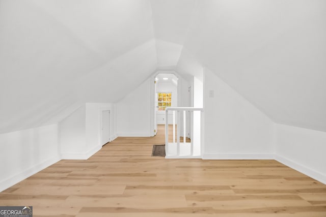 bonus room with vaulted ceiling and light wood-type flooring