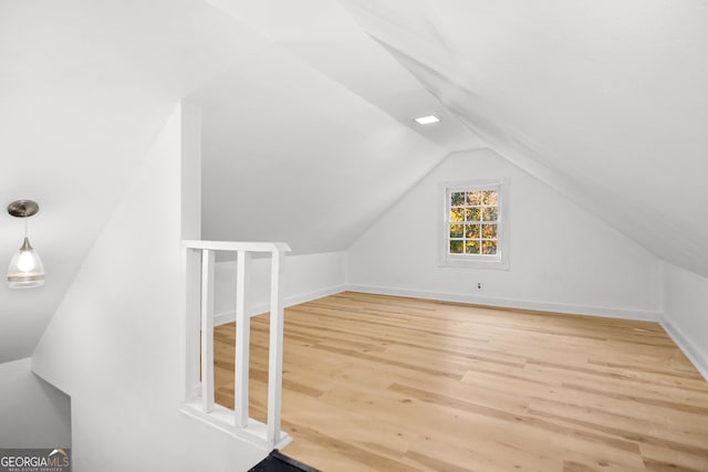 additional living space featuring wood-type flooring and vaulted ceiling