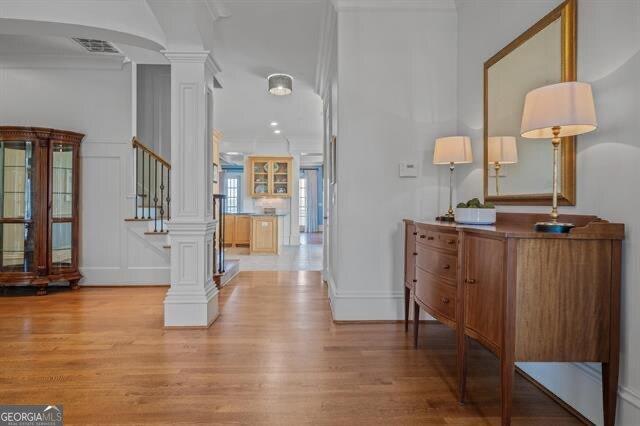 entryway with ornate columns, ornamental molding, and light hardwood / wood-style flooring