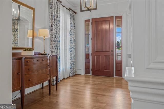 entryway with crown molding, a chandelier, and light hardwood / wood-style floors