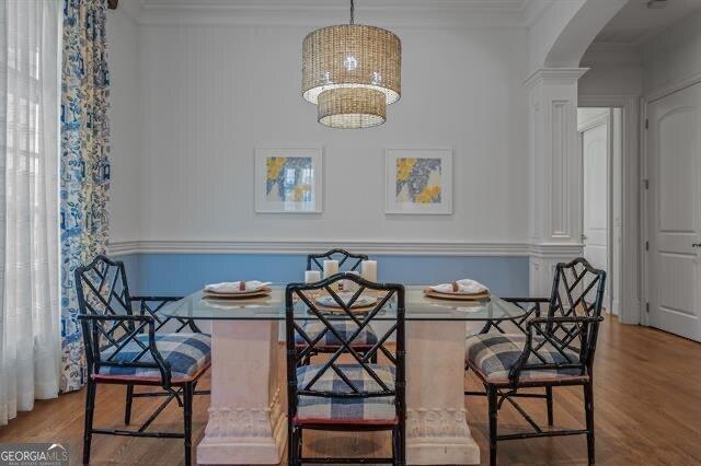 dining space featuring breakfast area, crown molding, hardwood / wood-style floors, and decorative columns