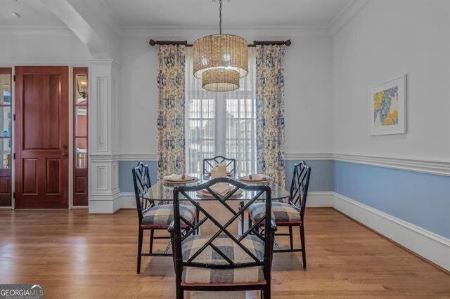 dining space featuring decorative columns, crown molding, and hardwood / wood-style floors