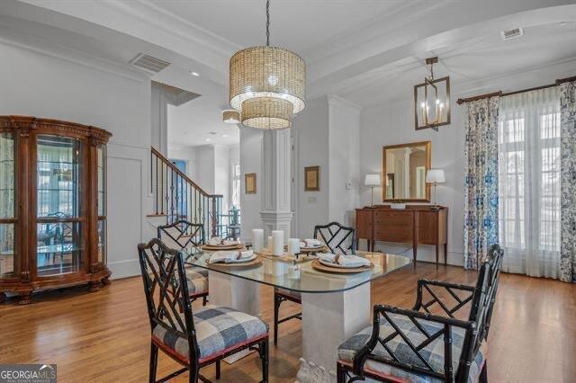 dining space with decorative columns, crown molding, a notable chandelier, and light wood-type flooring