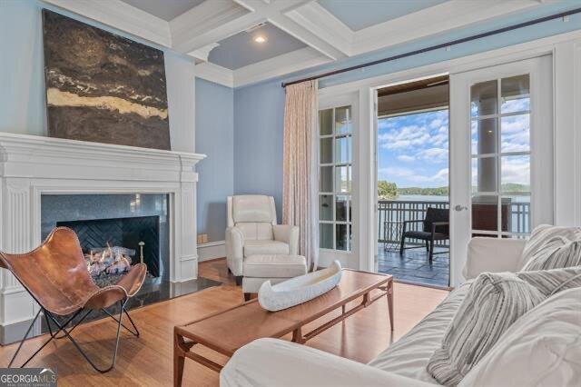 living area featuring light hardwood / wood-style flooring, a fireplace, coffered ceiling, and beamed ceiling