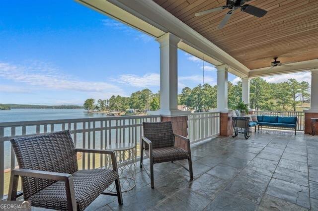 view of patio with a porch, ceiling fan, and a water view