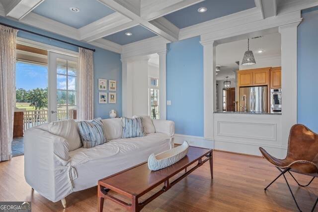 living room featuring coffered ceiling, decorative columns, crown molding, beam ceiling, and light hardwood / wood-style floors