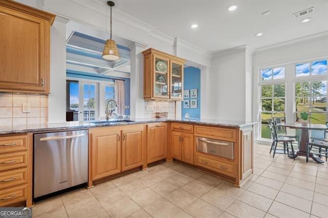 kitchen featuring sink, dishwasher, dark stone countertops, hanging light fixtures, and kitchen peninsula