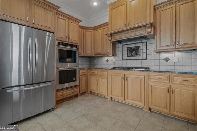 kitchen with crown molding, appliances with stainless steel finishes, custom range hood, dark stone counters, and backsplash