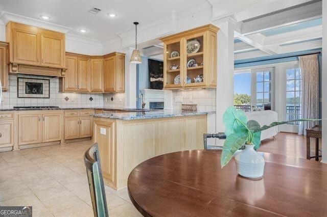 kitchen featuring hanging light fixtures, ornamental molding, stainless steel gas stovetop, light stone countertops, and backsplash