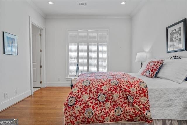 bedroom with wood-type flooring and crown molding