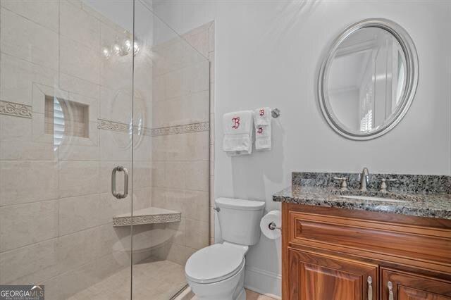 bathroom featuring vanity, toilet, and an enclosed shower