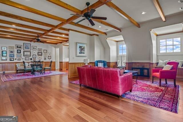 living room featuring beamed ceiling, ceiling fan, and wood-type flooring