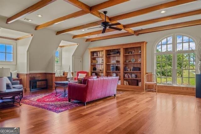 living room with hardwood / wood-style flooring, ceiling fan, a wealth of natural light, and beam ceiling