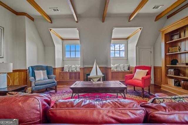 living room with wood-type flooring, crown molding, and beam ceiling