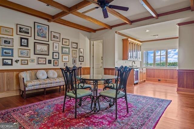 dining area featuring beam ceiling, light hardwood / wood-style floors, and wood walls