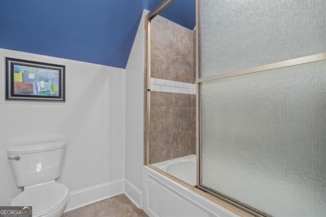 bathroom featuring enclosed tub / shower combo and toilet