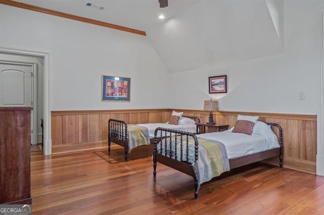 bedroom with lofted ceiling, hardwood / wood-style floors, and wood walls