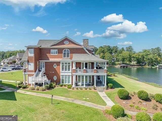 view of front of house with a front yard, a balcony, and a water view