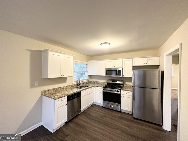 kitchen with sink, dark wood-type flooring, stainless steel appliances, white cabinets, and dark stone counters