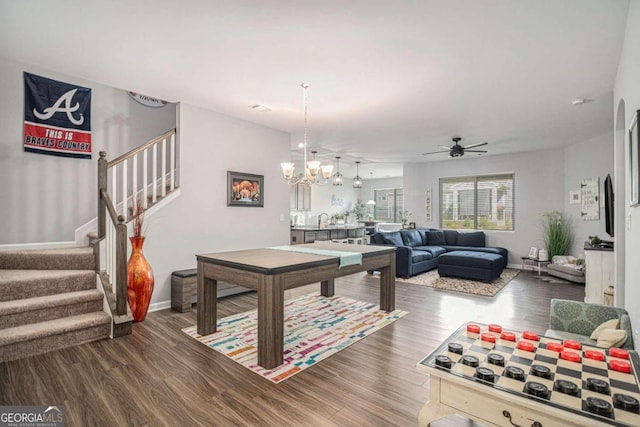 recreation room featuring dark wood-type flooring and ceiling fan with notable chandelier