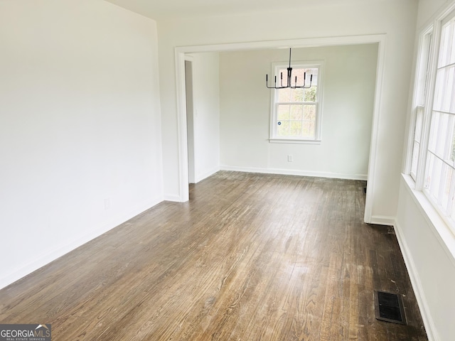 unfurnished dining area with dark hardwood / wood-style flooring and an inviting chandelier