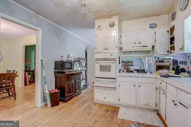 kitchen with white appliances, tile countertops, light hardwood / wood-style floors, and white cabinets