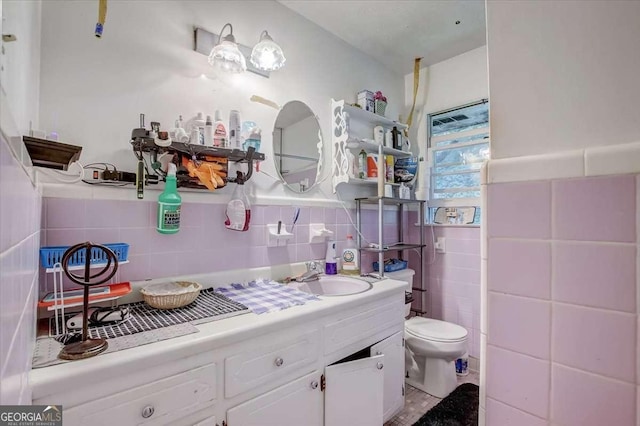 bathroom featuring vanity, toilet, and tile walls