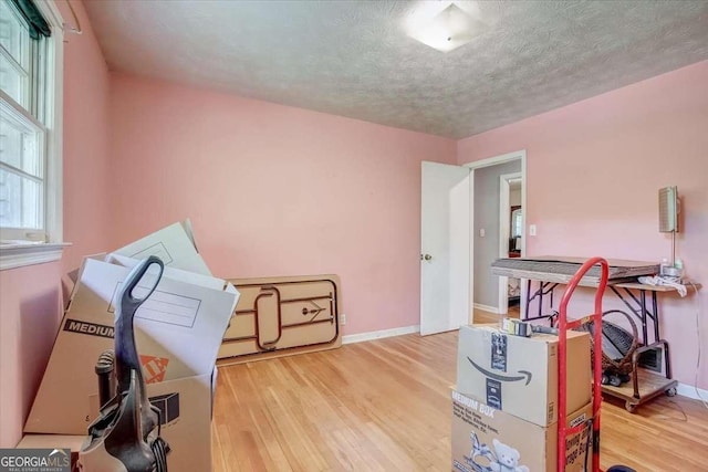 misc room with light hardwood / wood-style floors and a textured ceiling