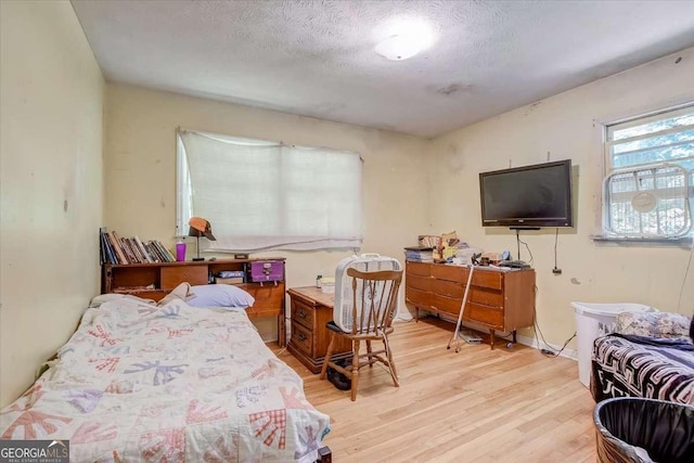 bedroom with a textured ceiling and light hardwood / wood-style flooring