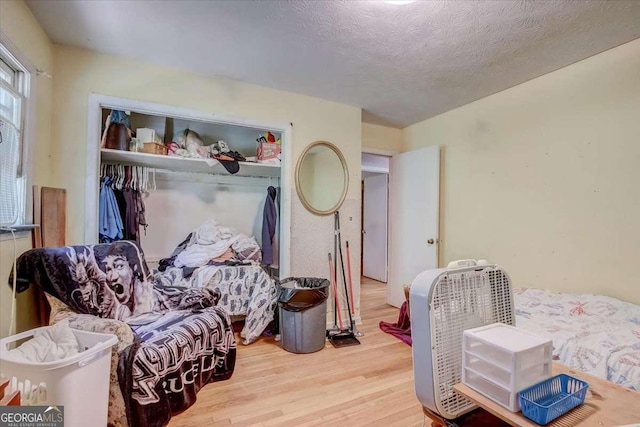 bedroom with a closet, a textured ceiling, and light wood-type flooring