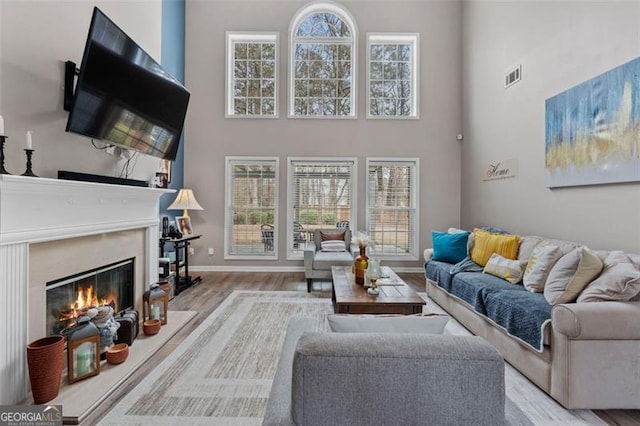 living room featuring light hardwood / wood-style flooring, plenty of natural light, and a high ceiling