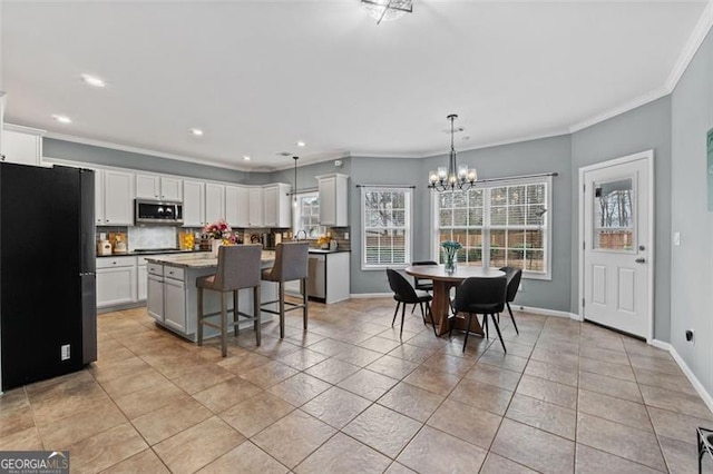 kitchen with pendant lighting, stainless steel appliances, a kitchen breakfast bar, white cabinets, and a kitchen island