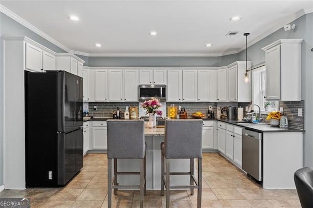 kitchen with a kitchen island, appliances with stainless steel finishes, sink, and white cabinets