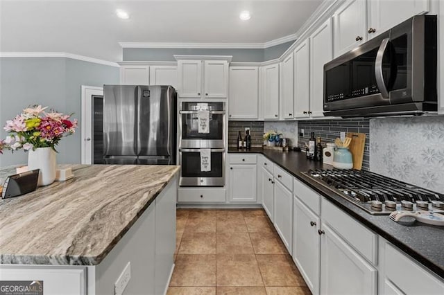 kitchen featuring light tile patterned floors, crown molding, stainless steel appliances, and white cabinets