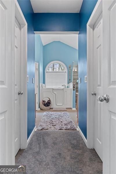 hall with vaulted ceiling and carpet