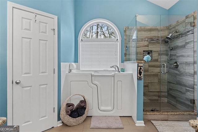 bathroom featuring lofted ceiling, tile patterned flooring, and a shower with shower door