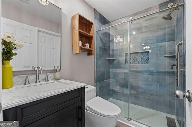 bathroom featuring vanity, a shower with door, and toilet