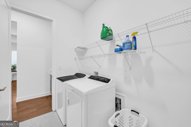 clothes washing area featuring washing machine and clothes dryer and light wood-type flooring